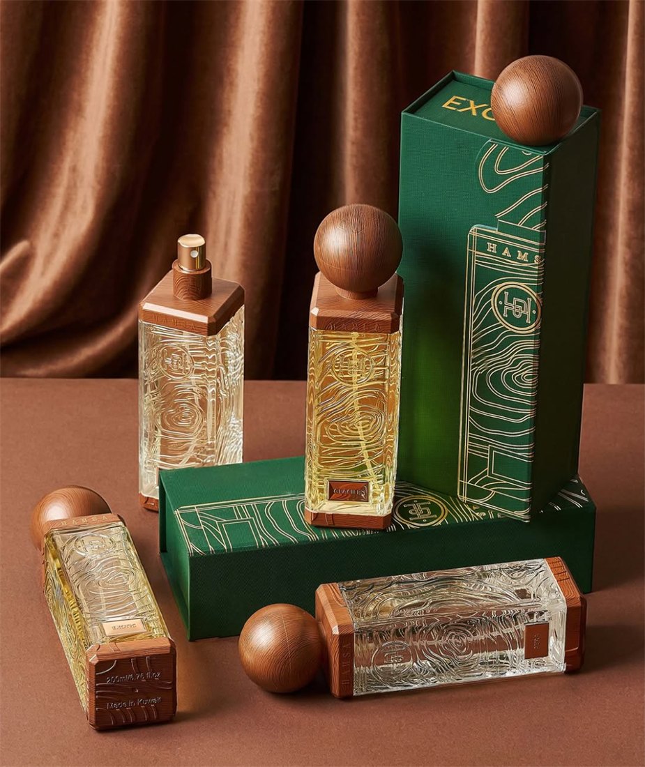 Hamsa Exotic collection bottles, including a spray-top perfume, displayed with their tall green box against a velvet curtain